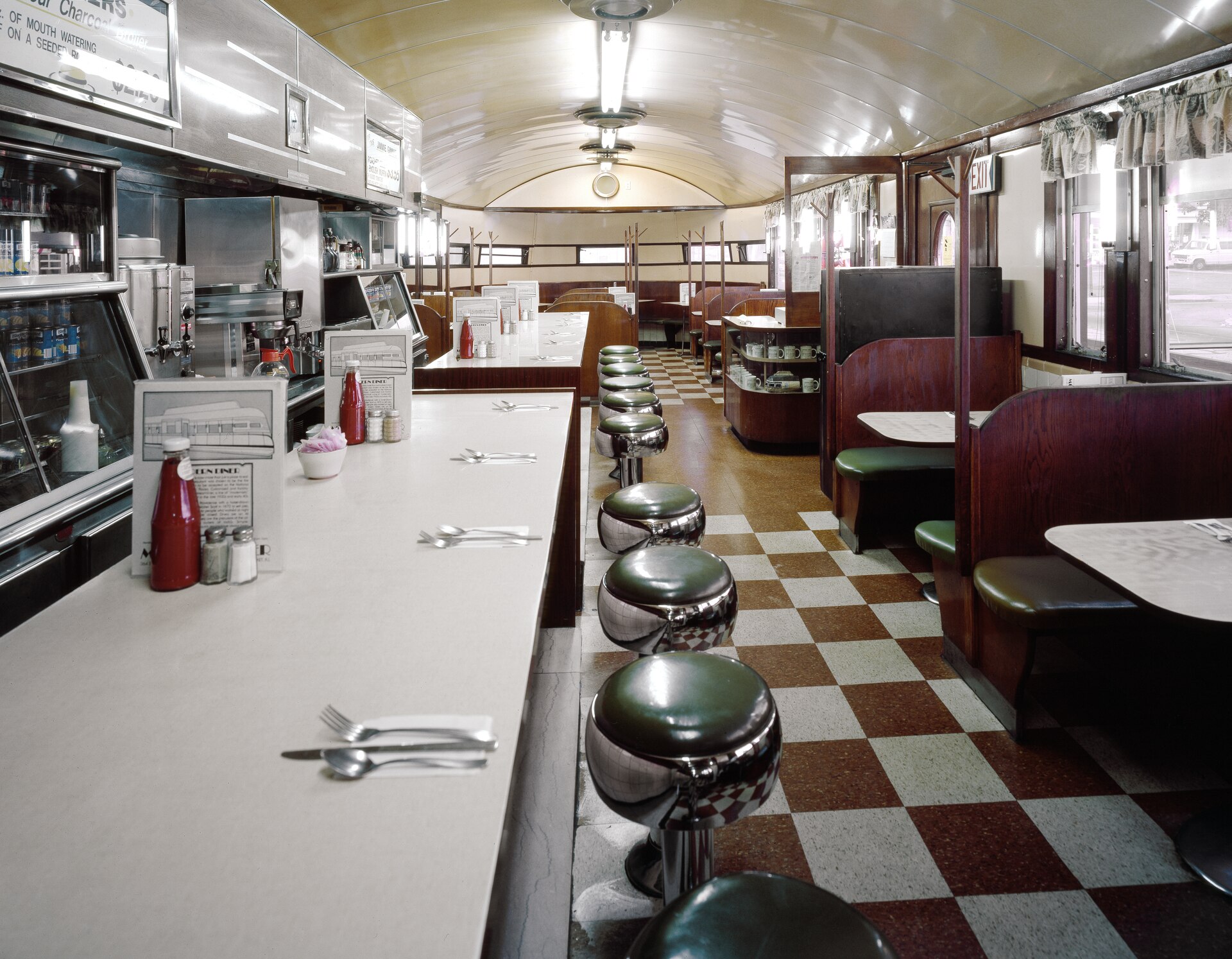 Green counter stools, wooden booths, and a checkerboard floor inside the Modern Diner